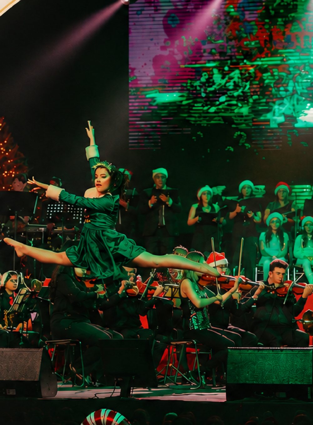 Bailarina en salto sobre el escenario de Jingle Night con la orquesta al fondo