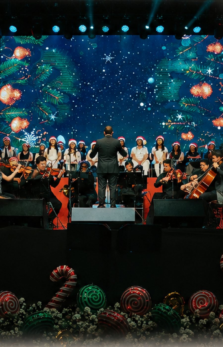 Coro y orquesta de Jingle Night sobre el escenario ante una pantalla navidena